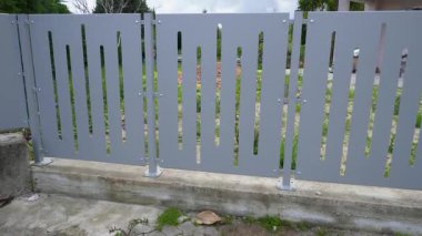 Dikey kesikli modern metal çitler. Dekoratif lazer kesimli, sağlam beton bir zemine monte edilmiş oval çitler. Kentsel mimari için modern minimalist tasarım, özel evler