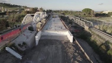 Dağ kıyısında bir köprü inşaatı. Çift amaçlı kemer köprüsünün drone görüntüsü. Deniz kıyısında bir dağ nehri boyunca bir köprü inşa edilecek..