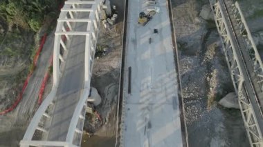 Dağ kıyısında bir köprü inşaatı. Çift amaçlı kemer köprüsünün drone görüntüsü. Deniz kıyısında bir dağ nehri boyunca bir köprü inşa edilecek..