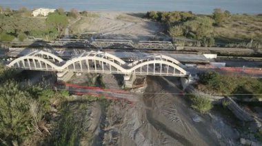 Dağ kıyısında bir köprü inşaatı. Çift amaçlı kemer köprüsünün drone görüntüsü. Deniz kıyısında bir dağ nehri boyunca bir köprü inşa edilecek..