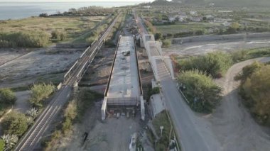 Dağ kıyısında bir köprü inşaatı. Çift amaçlı kemer köprüsünün drone görüntüsü. Deniz kıyısında bir dağ nehri boyunca bir köprü inşa edilecek..