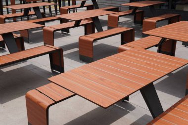 Tasarımcı masaları ve banklar. Şık ve iyi organize edilmiş açık hava oturma alanı. Minimalist tasarım, kamusal alanlar, kafeler veya kampüs bahçeleri için ideal, şık ve işlevsel bir ortam yaratır.