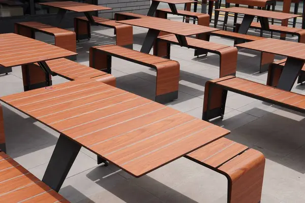 Tasarımcı masaları ve banklar. Şık ve iyi organize edilmiş açık hava oturma alanı. Minimalist tasarım, kamusal alanlar, kafeler veya kampüs bahçeleri için ideal, şık ve işlevsel bir ortam yaratır.