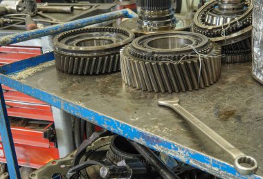 Parçalanmış bir vites kutusu. Parçalanmış vites kutusu bileşenleriyle dolu bir tezgah - dişliler, civatalar, yataklar ve şaftlar sistemli bir şekilde yerleştirilmiş.