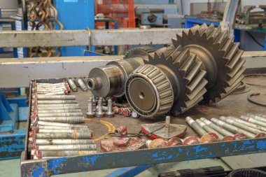 Parçalanmış bir vites kutusu. Parçalanmış vites kutusu bileşenleriyle dolu bir tezgah - dişliler, civatalar, yataklar ve şaftlar sistemli bir şekilde yerleştirilmiş.