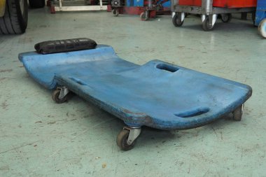 Otomotiv sürüngeni. Tamirci. Tamirat ve tamirat için aracın altında hareket eden tamircilerin ayrılabileceği bir destek..