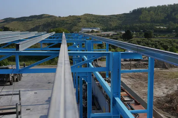 Çelik bir yapı kuruyorum. Çelik bir yapının inşa edildiği bir inşaat alanı. Ağır zincirleri olan bir vinç. İskele işçilere destek sağlıyor. Parlak mavi ve endüstriyel manzara.