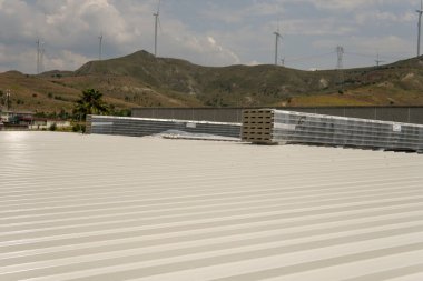 İnşaat halindeki çelik bir yapının tepesinde metal levha. Polyester sandviç panelleri. Bu resim, endüstriyel bir binanın metal çatısındaki yapı malzemelerini gösteriyor..