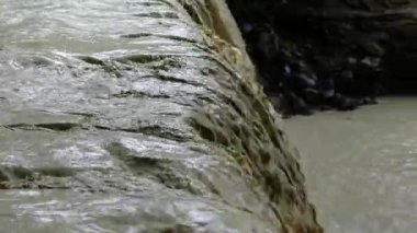 Kahverengi nehir yağmurdan sonra akar. Dağlardaki şiddetli yağmurlardan sonra, dağ nehri çamurlu ve hızlı bir akıntıya dönüştü. Şiddetli yağmurlar ani bir su artışına neden oldu, toprağı taşıyarak..
