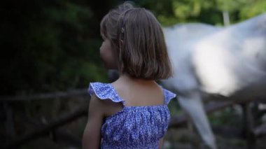 Küçük kız ve beyaz at. Bivongi, Reggio Calabria 06.22.2025 eyerli atlar, kovboy şapkaları. Calabria 'nın pitoresk bölgesinde olay, turizm