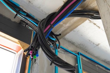 Bükülmüş plastik borulardaki elektrik kabloları. Borular, inşaat sektörünün altyapısı, mühendislik sistemleri ve süreçleri için elektrik tesisatı çalışmalarının bir parçası..