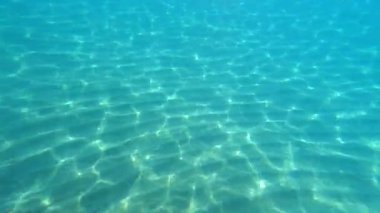 Kamera, kristal berrak suların altında beyaz kumu aşıyor. Sonra da güney İtalya 'daki işlek bir gezinti alanında güneşli bir sahili ortaya çıkarıyor..