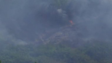 Dağlarda orman yangını, otobandan görüldüğü gibi. Hareket halindeki bir arabadan alınan bu dramatik video dağların yamaçlarında yükselen orman yangınlarını ve gökyüzüne yükselen yoğun dumanı gösteriyor..