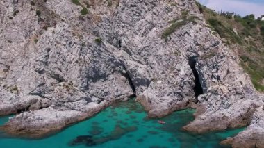 Turkuaz deniz manzarası, sudaki granit kayalar, suyun üzerinde süzülen tekne ve yatlar, pedal süren turistler ve çarpıcı bir Akdeniz cennetinde keyif tekneleri.