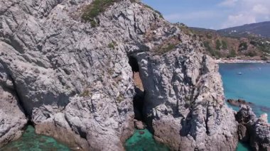 Turkuaz deniz manzarası, sudaki granit kayalar, suyun üzerinde süzülen tekne ve yatlar, pedal süren turistler ve çarpıcı bir Akdeniz cennetinde keyif tekneleri.