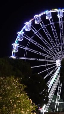 Gece gökyüzüne karşı dönme dolap. Büyük, detaylı dönme dolap eğlence, rahatlama ve eğlence parkı atmosferini simgeliyor..