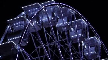 Gece gökyüzüne karşı dönme dolap. Büyük, detaylı dönme dolap eğlence, rahatlama ve eğlence parkı atmosferini simgeliyor..