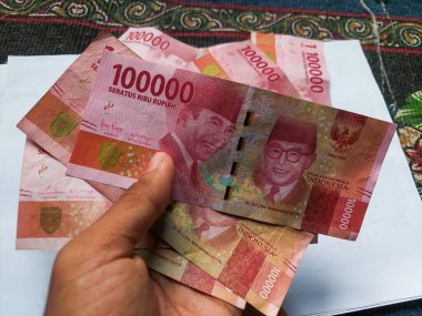 100.000 rupiah banknotları el ele tutuştu.