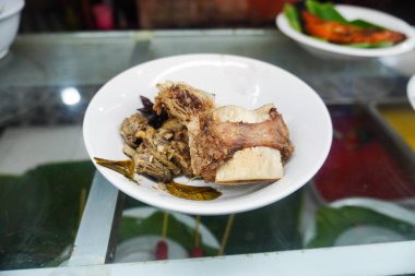 Indonesian food, Padang cuisine buffet: Fish in coconut milk, fried fish, grilled fish, beef and other dishes are displayed in a glass display case. clipart