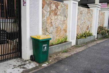 Evin ön çitindeki yeşil çöp tenekesi.