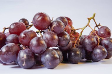 Beyaz arka planda taze üzümler. Bu fotoğraf poster tasarımlarında, tebrik kartlarında veya meyvelerle ilgili makalelerde kullanılmak için idealdir..