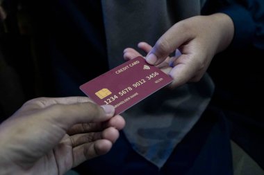 Bir adamın kredi kartını ödemesi için bir kadına verirken çekilmiş bir fotoğraf.