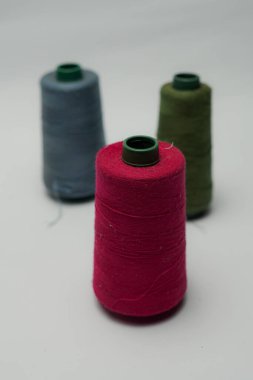 Beyaz arkaplanı olan bir dikiş makinesine dikiş dikmek için renkli dikiş ipliği aksesuarları