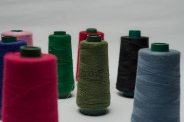 Beyaz arkaplanı olan bir dikiş makinesine dikiş dikmek için renkli dikiş ipliği aksesuarları