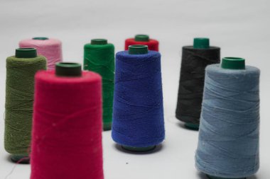 Beyaz arkaplanı olan bir dikiş makinesine dikiş dikmek için renkli dikiş ipliği aksesuarları