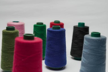 Beyaz arkaplanı olan bir dikiş makinesine dikiş dikmek için renkli dikiş ipliği aksesuarları
