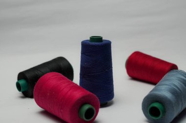 Beyaz arkaplanı olan bir dikiş makinesine dikiş dikmek için renkli dikiş ipliği aksesuarları