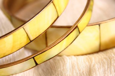 Kireç yeşili sert bilezikler kaba bej kumaşta.