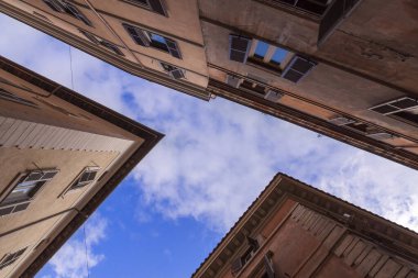 Mavi gökyüzüne bakarken binalar arasındaki darlık. Binaların tarzını takdir edebilir.