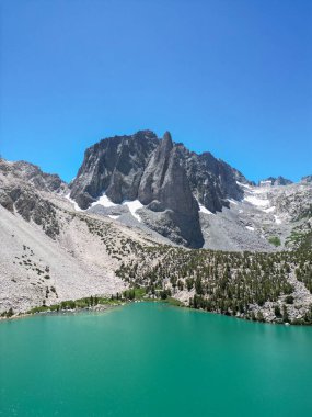 Inyo Ulusal Ormanı 'ndaki patikalar, John Muir Wilderness, güneşli bir günde dağ gölü, dağların arkasındaki dağ ormanları ve berrak bir göl, bulutsuz bir gökyüzüne karşı turkuaz göl.