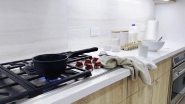 Mutfakta yemek pişiren, ocakta yemek pişiren, yanında duran, kahvaltı hazırlayan bir kadın.