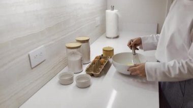 Genç bir kadın mutfağında yemek pişiriyor, malzemeleri bir tabakta yoğuruyor, kahvaltı, ev yapımı pişirme, evde pişirme, hamur hazırlıyor.