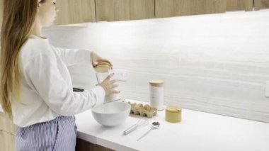 Genç bir kadın mutfağında yemek pişiriyor, malzemeleri bir tabakta yoğuruyor, kahvaltı, ev yapımı pişirme, evde pişirme, hamur hazırlıyor.