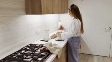 Genç bir kadın mutfağında yemek pişiriyor. Malzemeleri tartıyor. Pul, kahvaltı, ev yapımı pişirme, evde pişirme, hamur pişirme.