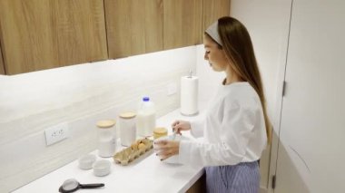 Kadın ev mutfağında krep pişiriyor, hamur yoğuruyor, evde tatlı pişiriyor, kadın elleri çerçeveyi kapatıyor.