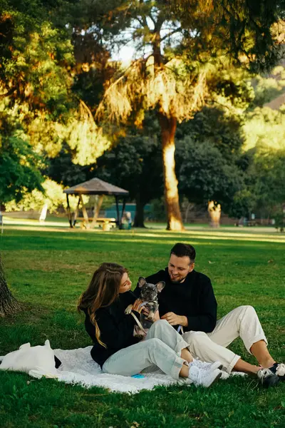 Parkta köpekle gezen bir aile, parkta tasmayla dolaşan bir buldog yavrusu, evin dışında evcil hayvan vakit geçiren genç bir çift.