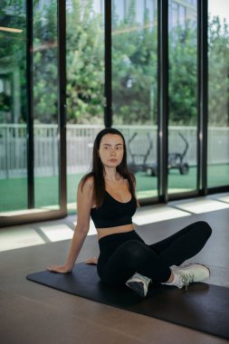 Evde egzersiz yapan genç bir kadın, paspas, esneme ve yoga, fiziksel sağlık, ev sağlığı, beden eğitimi.