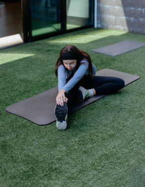 Spor paspası, esneme ve yoga üzerinde egzersiz yapan genç bir kadın, güneşli bir günde dışarıda fiziksel sağlık, ev sağlığı.