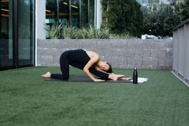 Pilates yoga yapan bir kadın, esneme egzersizleri yapan genç bir kadın, ev sağlığı, spor paspası üzerinde vücut esneme hareketleri yapan güzel bir kadın., 