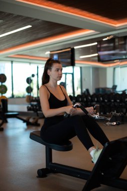 wide grip row, a woman exercising in the gym Narrow grip row , pumping up arm muscles on a machine clipart