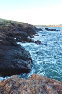 Görüntü Punta Ballena 'da, Uruguay' daki Punta del Este yakınlarında çarpıcı bir sahne yakalıyor. Okyanus dalgaları kayalık kıyı şeridine çarpar köpüklü beyaz su püskürtür.