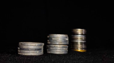 İş büyümesini simgeleyen para yığınları siyah arkaplanlı.