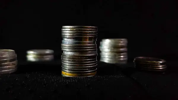 İş büyümesini simgeleyen para yığınları siyah arkaplanlı.