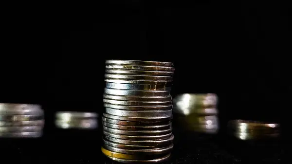 İş büyümesini simgeleyen para yığınları siyah arkaplanlı.