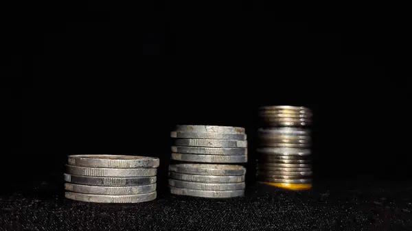 İş büyümesini simgeleyen para yığınları siyah arkaplanlı.