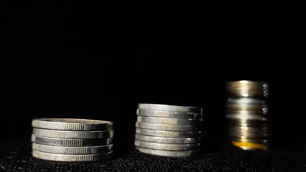 İş büyümesini simgeleyen para yığınları siyah arkaplanlı.